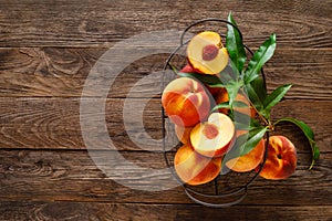 Ripe peaches with leaves in basket on wooden table