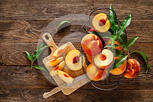 Ripe peaches with leaves in basket on wooden table