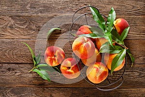 Ripe peaches with leaves in basket on wooden table