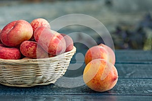 Ripe peaches in a wicker basket on a dark wooden background
