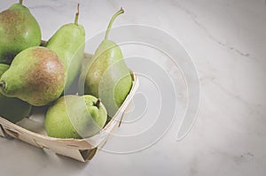 Ripe pears in a wattled box/ripe pears in a wattled box on a white marble background, top view and copy space