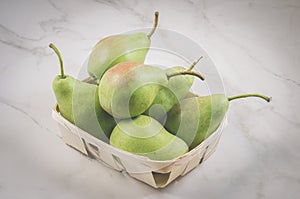 Ripe pears in a wattled box/ripe pears in a wooden box on a white marble background, selective focus