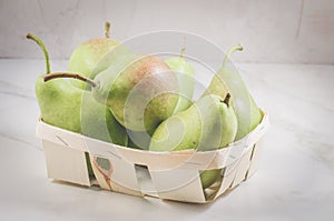 Ripe pears in a wooden box/ripe pears in a wooden box on a white marble background, selective focus