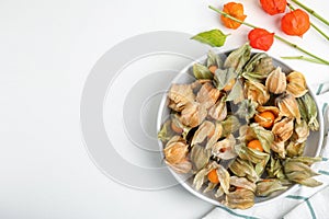 Ripe physalis fruits with dry husk and colorful sepals on white table, flat lay. Space for text