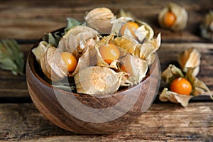 Ripe physalis fruits with dry husk on wooden table, closeup