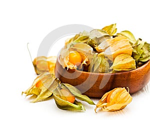 Ripe physalis in wooden bowl on white background