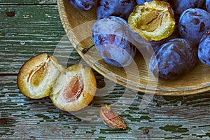 Ripe plum in wooden plate, on old table