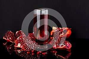 Ripe pomegranate fruit with leaves on black background.