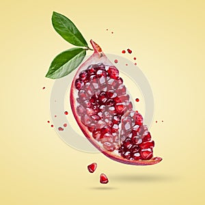 A ripe pomegranate with seeds and leaves flying in the air. Background with pomegranate fruit.