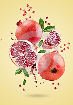 A ripe pomegranate with seeds and leaves flying in the air. Background with pomegranate fruit.