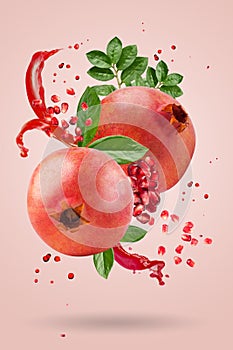 A ripe pomegranate with seeds and leaves flying in the air on a pink background. Background with pomegranate fruit.