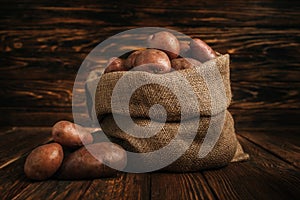 ripe potatoes in rustic sack on wooden background.