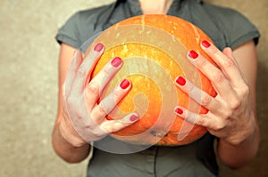 Ripe pumpkin in hands of woman