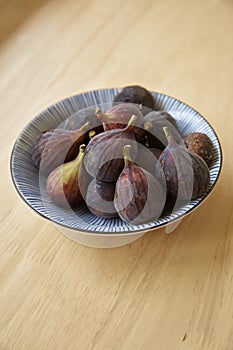 Ripe purple figs in dish on table