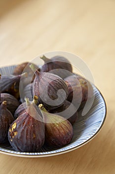 Ripe purple figs in dish on table