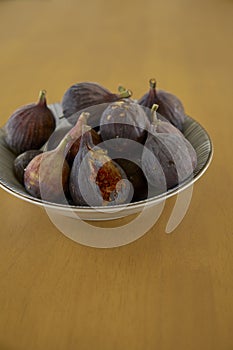 Ripe purple figs in dish on table