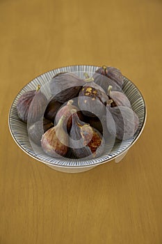 Ripe purple figs in dish on table