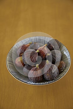 Ripe purple figs in dish on table