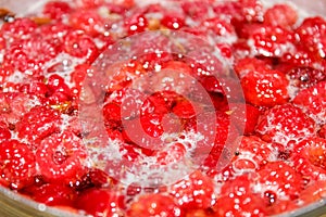 Ripe raspberries are boiling in a pot of water. Preparation of fresh compote