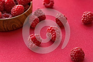 Ripe raspberries in a wooden container on a red background