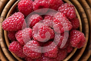 Ripe raspberries in a wooden container on a red background