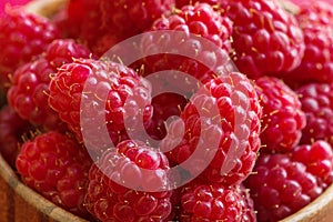 Ripe raspberries in a wooden container on a red background. Close up