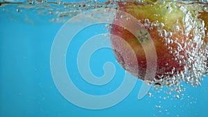 Ripe raw apples and air bubbles in water on blue clear background