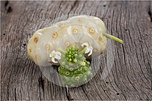 Ripe an raw noni fruits on an old wood background