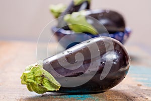 Ripe raw purple eggplants on a wooden background