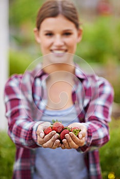 Ripe and ready. Cropped shot of a happy young woman holding a handful of fresh strawberries.