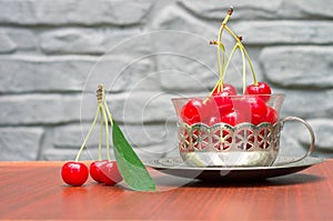 Ripe red cherries with cuttings in a cup with an iron