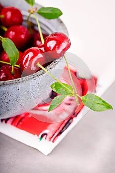 Ripe red cherries with leaves in a gray ceramic bowl, copy space