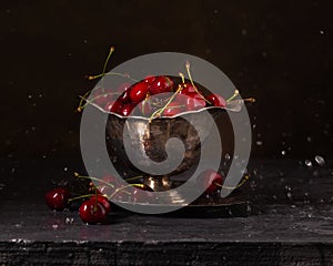 Ripe red cherries in a metal vase with splashing water