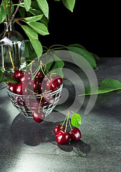 Ripe red cherries with tails in bowl, on grey surface