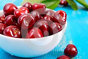 Ripe red cherry berries in a white ceramic bowl