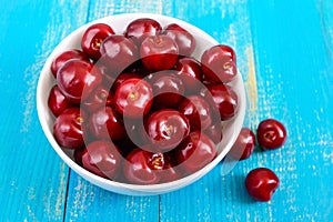 Ripe red cherry berries in a white ceramic bowl