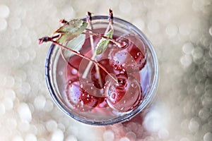 Ripe red cherry in a glass cup on a silver background with bokeh. Top view.Selective focus