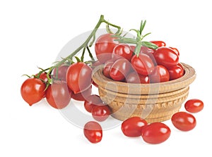 Ripe red cherry tomatoes branch in a wooden plate on a white background.