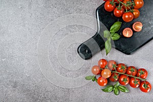 Ripe red cherry tomatoes with fresh basil leaves on stone table, top view copy space