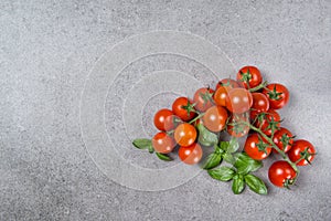 Ripe red cherry tomatoes with fresh basil leaves on stone table, top view copy space