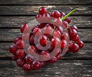 Ripe red grape. Pink bunch in a old rustic wooden table