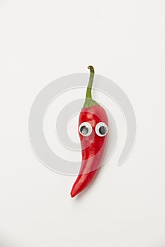 Ripe red hot peppers with funny eyes on a white background