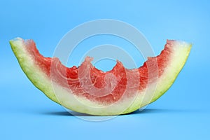 ripe red juicy watermelon slice bitten off on a blue background