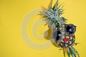 Ripe red lip pineapple with sunglasses on yellow background, co