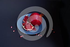 Ripe red pomegranate on a gray plate on a black background