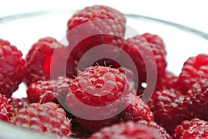 Ripe red raspberries in a glass bowl closeup