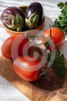 Ripe red Roma tomatoes in bowl with fresh herbs
