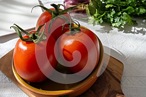 Ripe red Roma tomatoes in bowl with fresh herbs