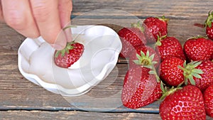 Ripe red strawberries dipped in a sour cream on wooden background