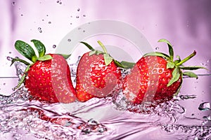 Ripe red strawberries are thrown and dropped into sparkling water, many bubbles